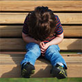 Photo of young boy sitting on a park bench.
